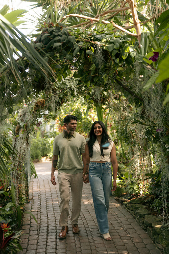 Couple laughing together surrounded by colorful flowers at Frederik Meijer Gardens engagement shoot