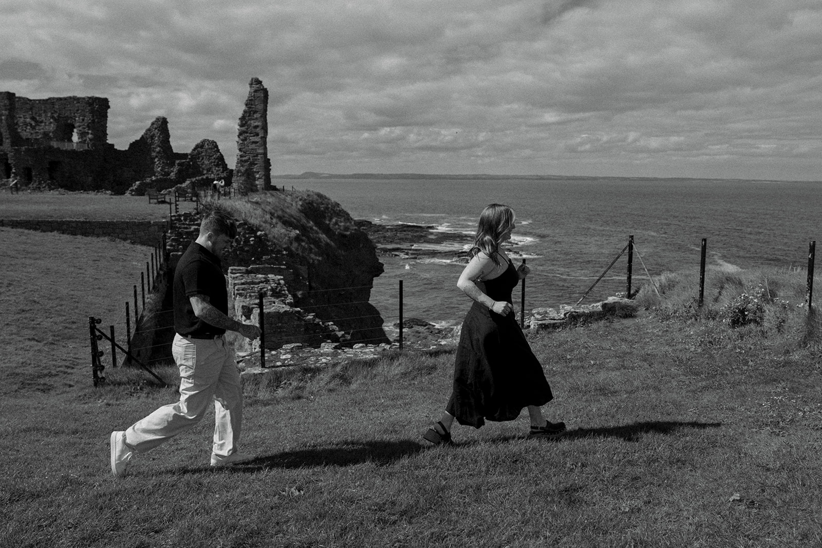 Couple walking hand in hand through ancient stone archway at Tantalon Castle Scotland