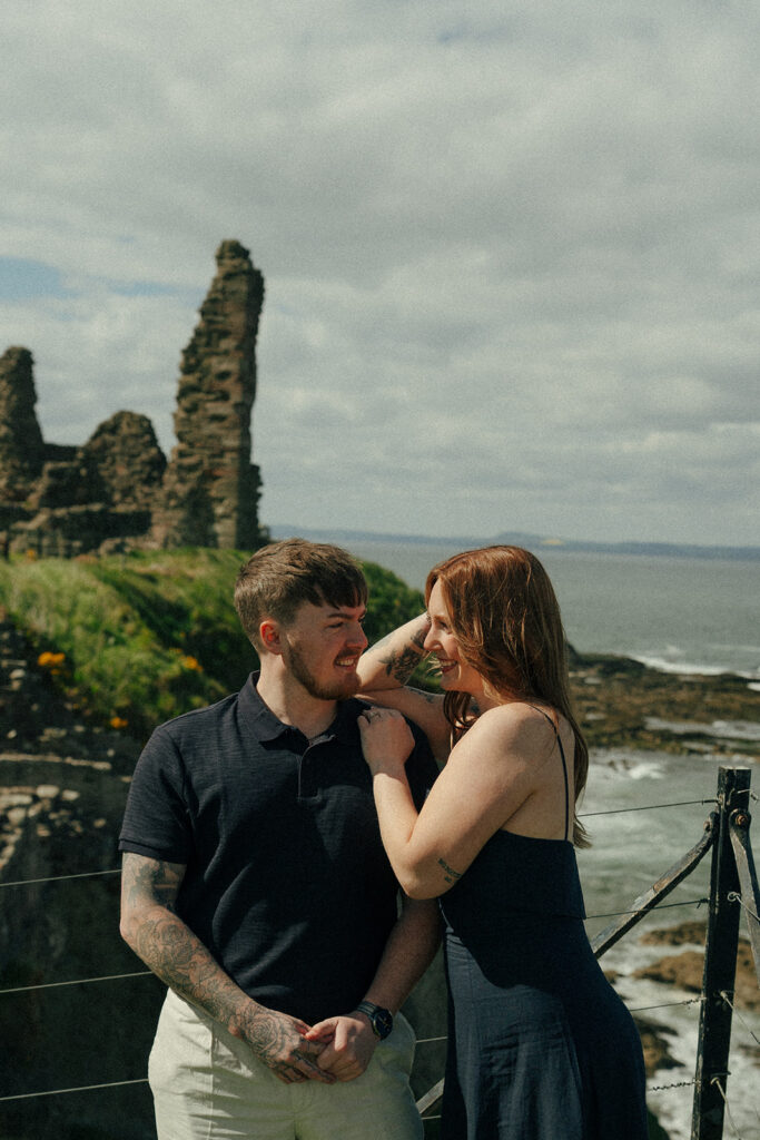Wide shot of couple standing in Tantalon Castle ruins with ocean views beyond
