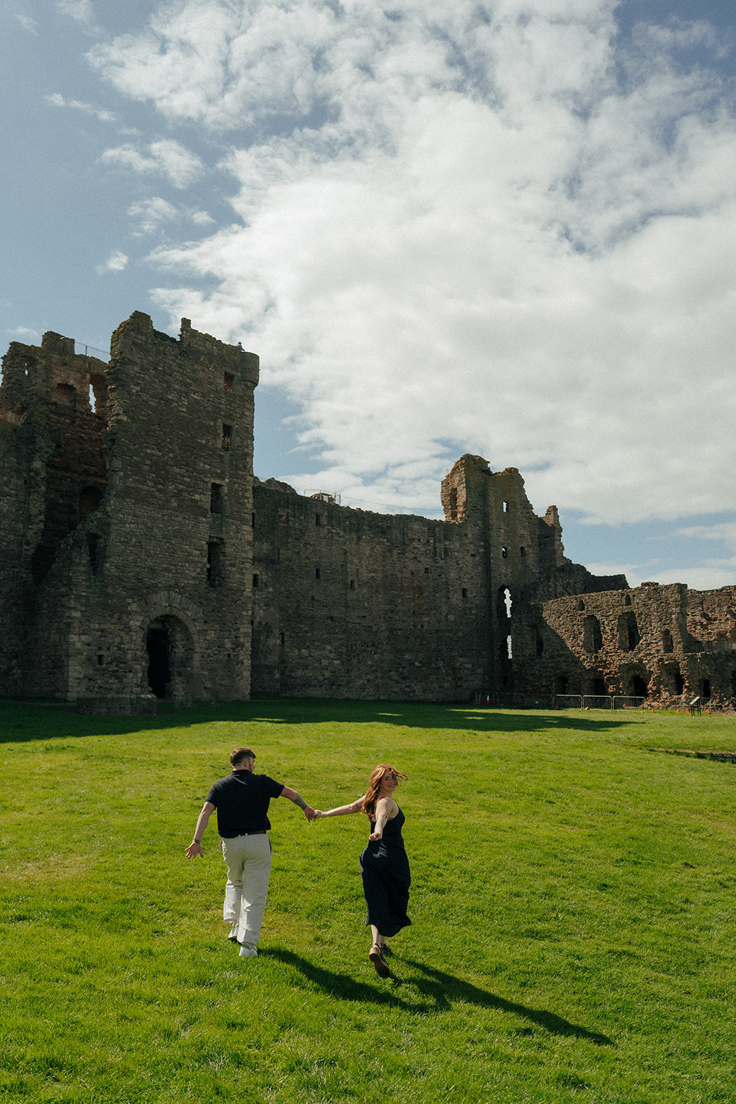 Engaged couple embracing at historic Tantalon Castle ruins overlooking Scottish coastline