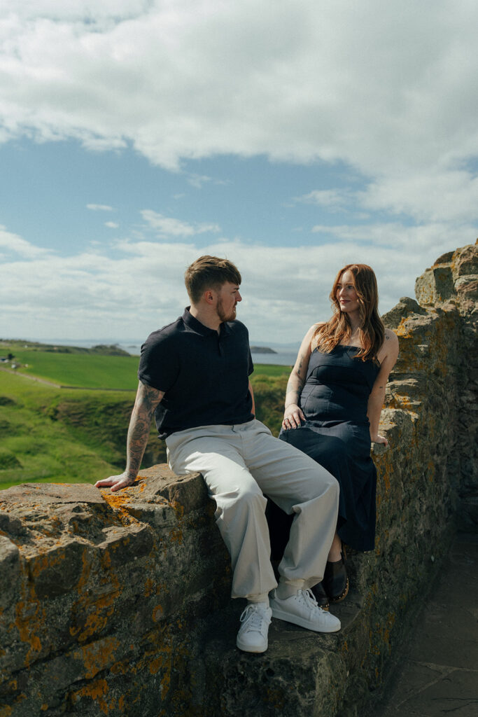 Bride-to-be laughing with fiance against Tantalon Castle stone walls Edinburgh