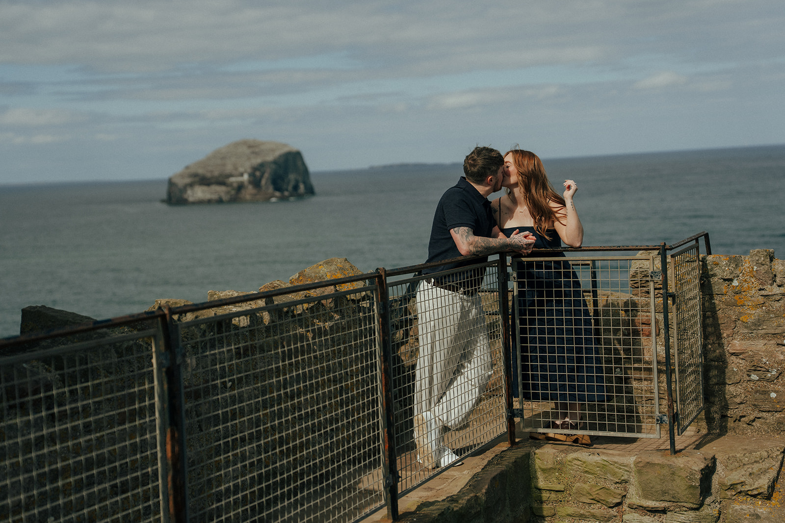 Couple walking away holding hands through Tantalon Castle gateway at blue hour