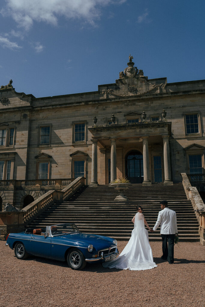Wedding couple embracing in front of Gosford House stone architecture at golden hour