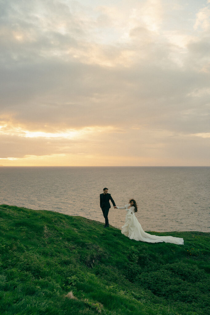 Couple kissing with waves crashing below during cliffs elopement photos Fast Castle Edinburgh Scotland