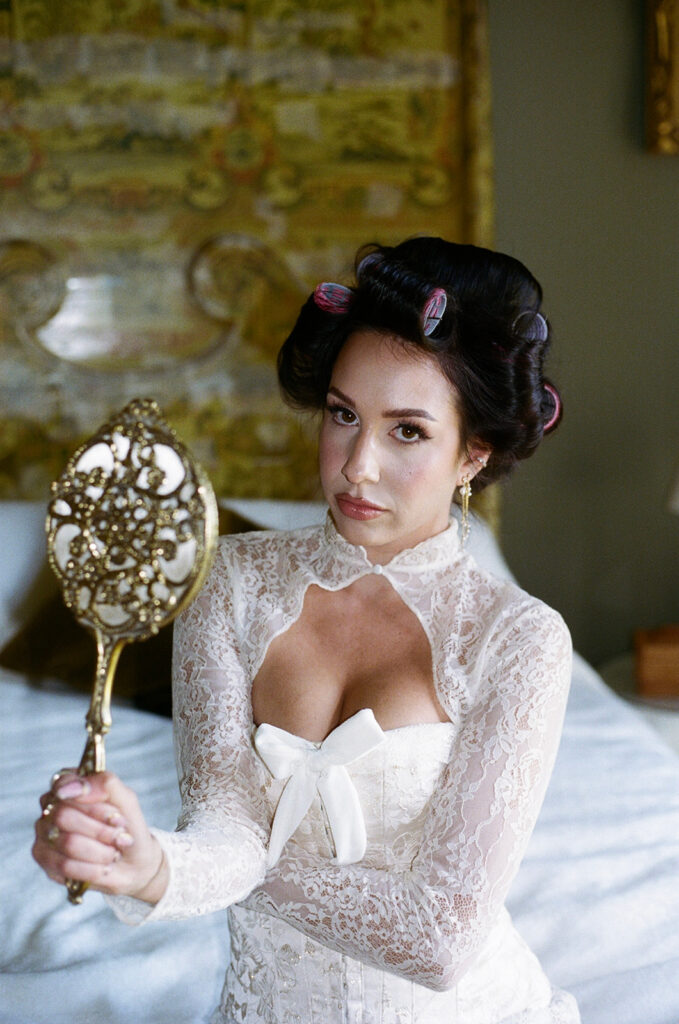 Bride holding luxury wedding bouquet in silk robe by window with soft natural light