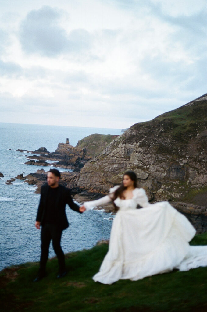 Bride and groom walking away during cliffs elopement photos Fast Castle Scotland sunset
